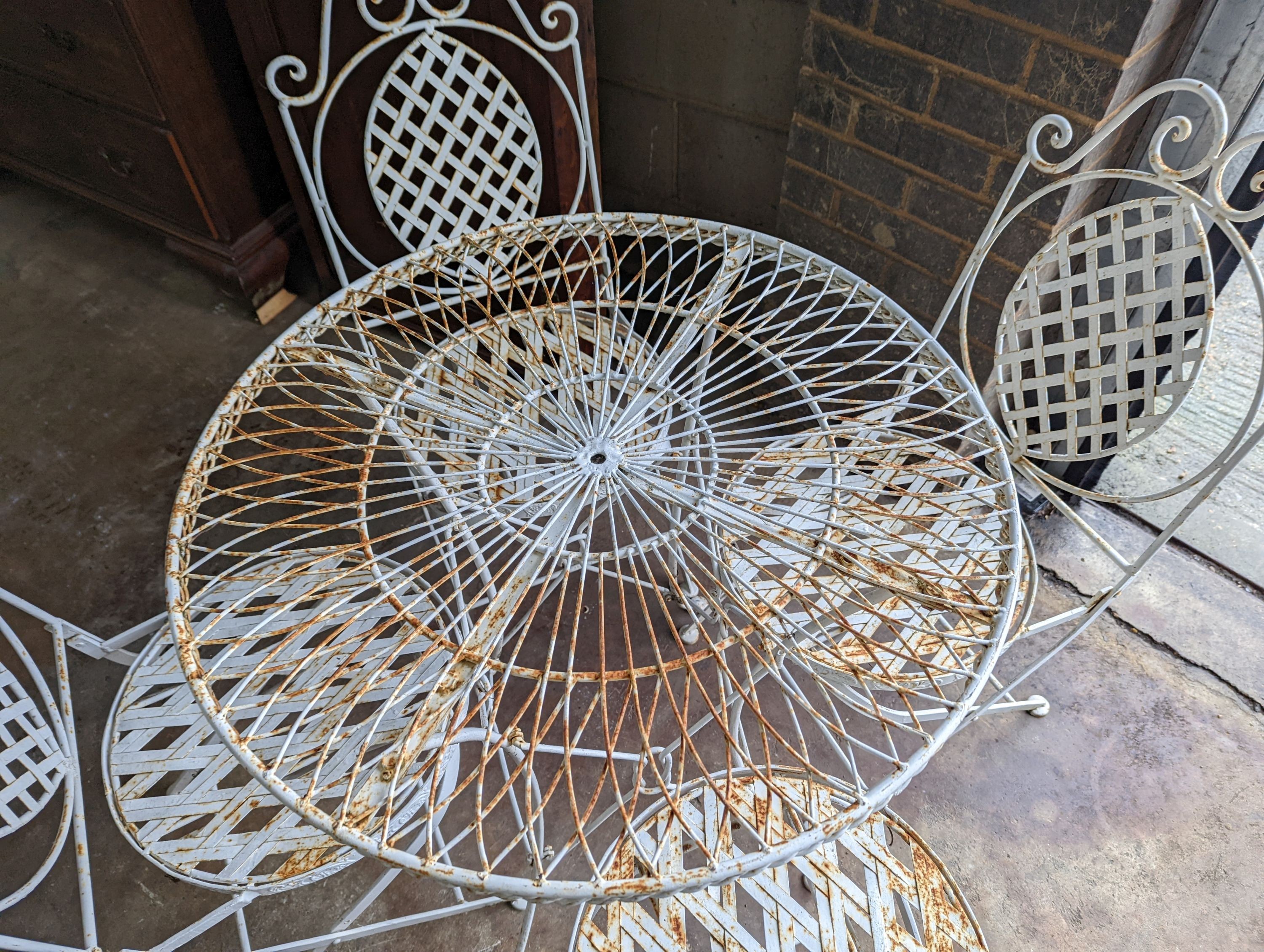 A circular painted wrought iron garden table, diameter 75cm, height 75cm together with four painted wrought iron folding garden chairs